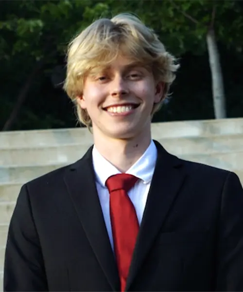 Lucas Nyman poses for a headshot in a suit with a red tie.