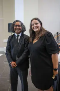 A man and a woman, both wearing black, pose for a picture.
