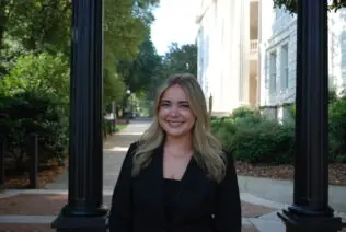 Danielle Zeitlin smiles in a headshot in front of the UGA Arch.