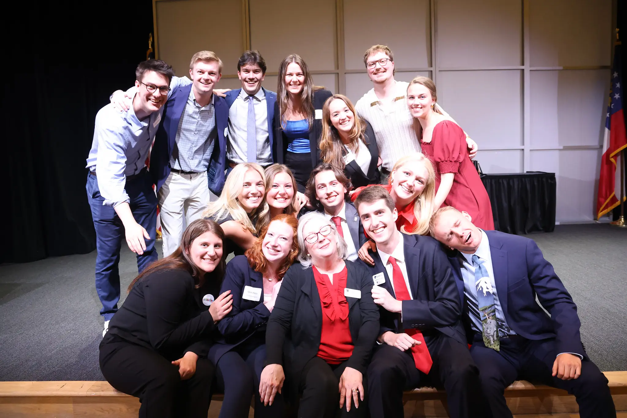 A group of students in business attire and their advisor smile while posing for a picture.