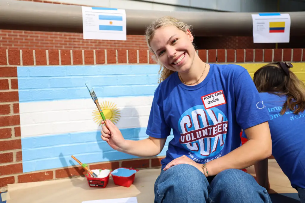 Mary Emma Coates sits in front of a part of a mural showcasing the Argentinian flag.