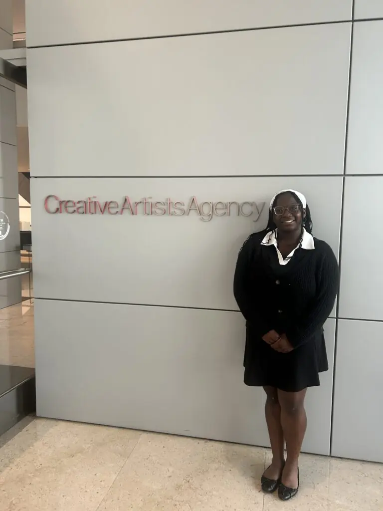 Ariel Greenway stands in front of a wall with the words Creative Artists Agency on the wall.