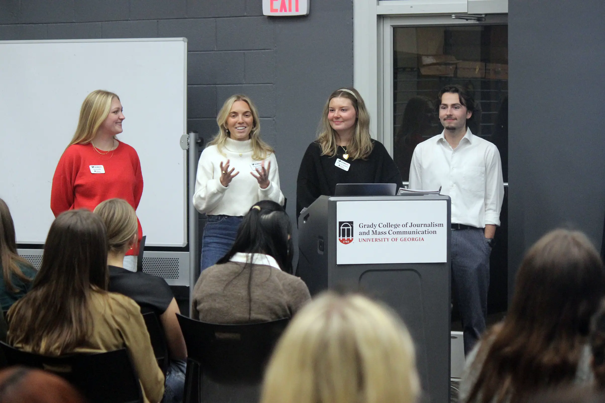 A group of four Talking Dog students stand behind a lectern and talk with the group.