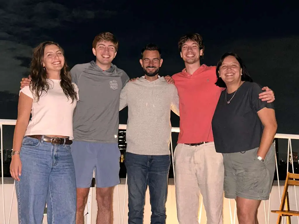 A nighttime picture of a group of students and their professor on a balcony.