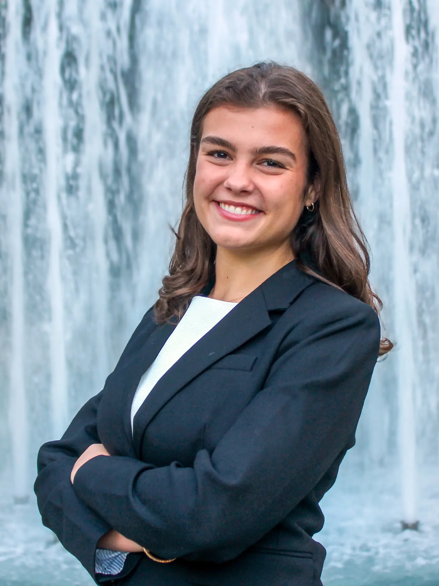 Outdoor headshot of Lizzie Hart with a fountain in the background.